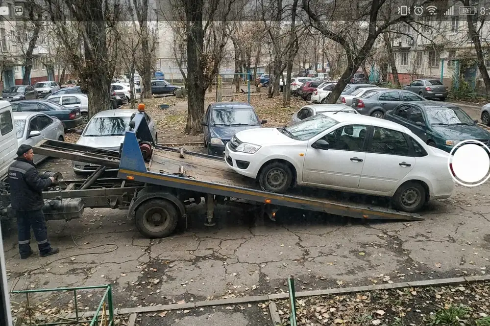 Эвакуатор грузит легковой автомобиль во дворе в Ростове-на-Дону